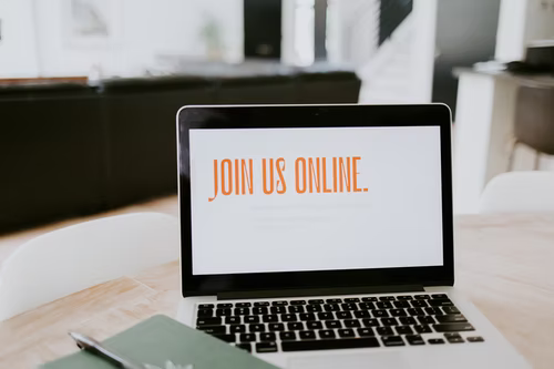 open laptop with the words “Join Us Online” written in orange font on the screen.