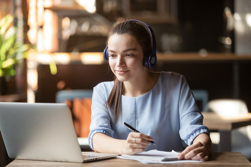 Focused woman wearing headphones using laptop